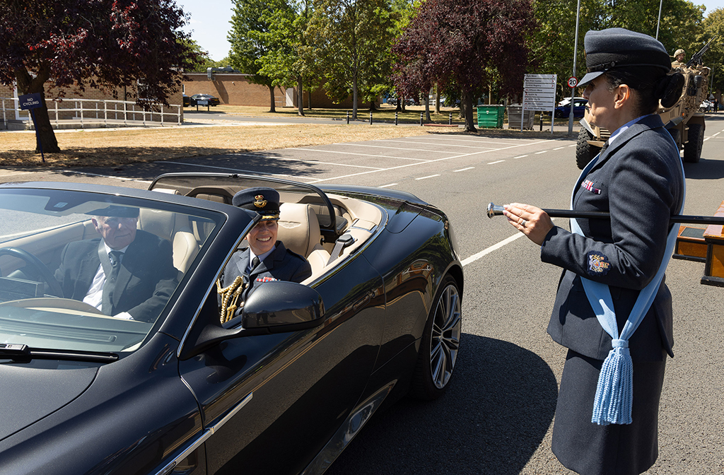 Group Captain Louise Henton is ceremoniously driven off the Station in a open top sports car, while being saluted by the Station Warrant Officer.
